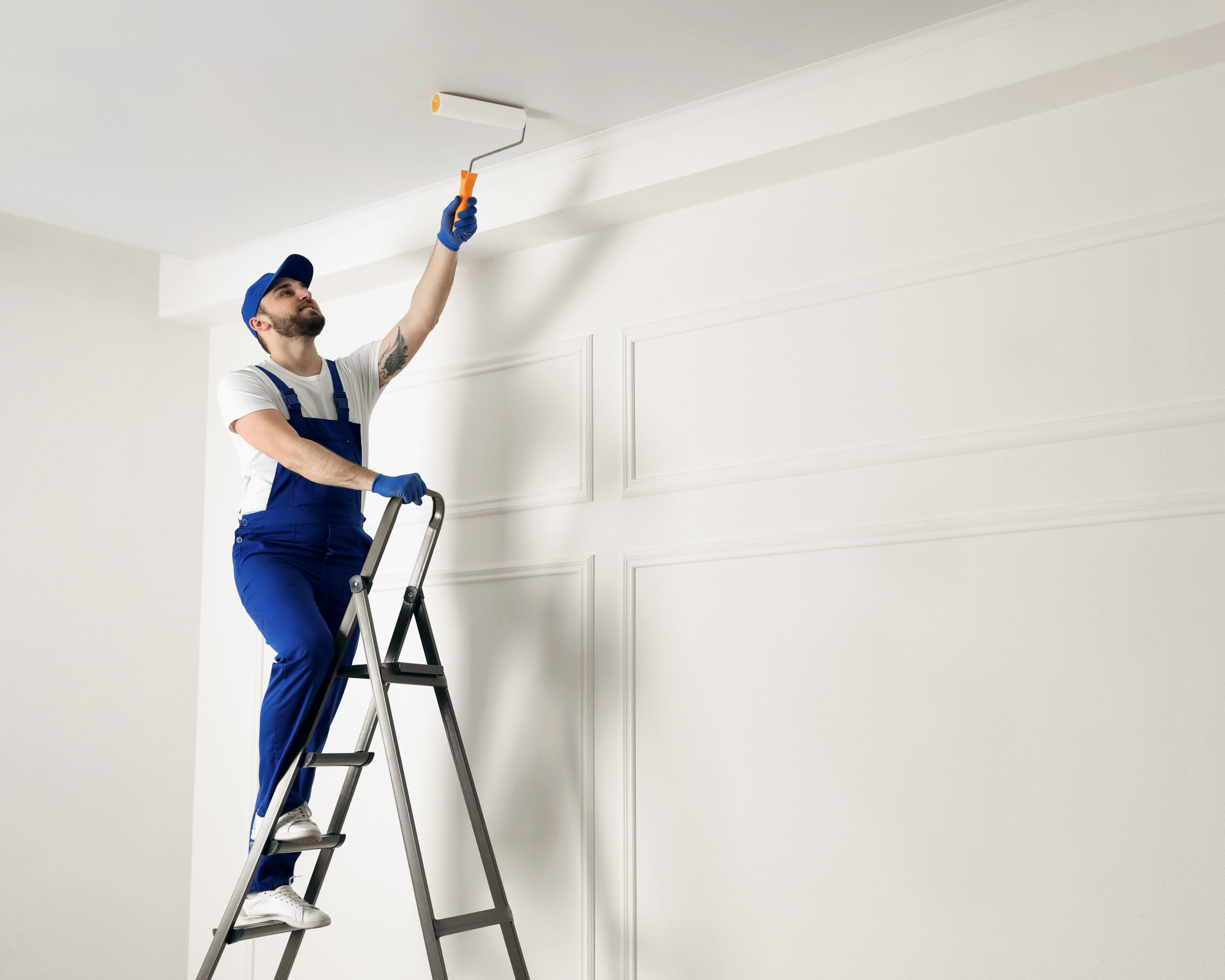 Painter painting ceiling of apartment white