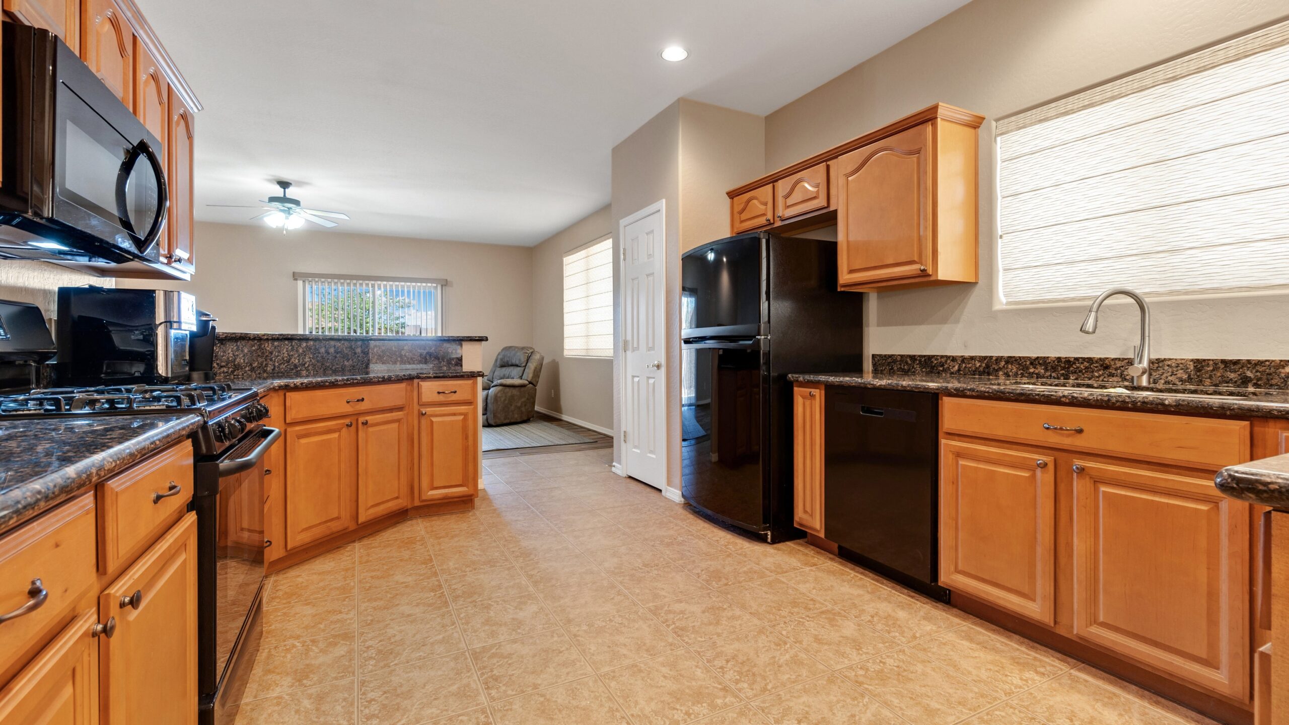 Spacious kitchen with wooden stained cabinets, tile floors and modern appliances