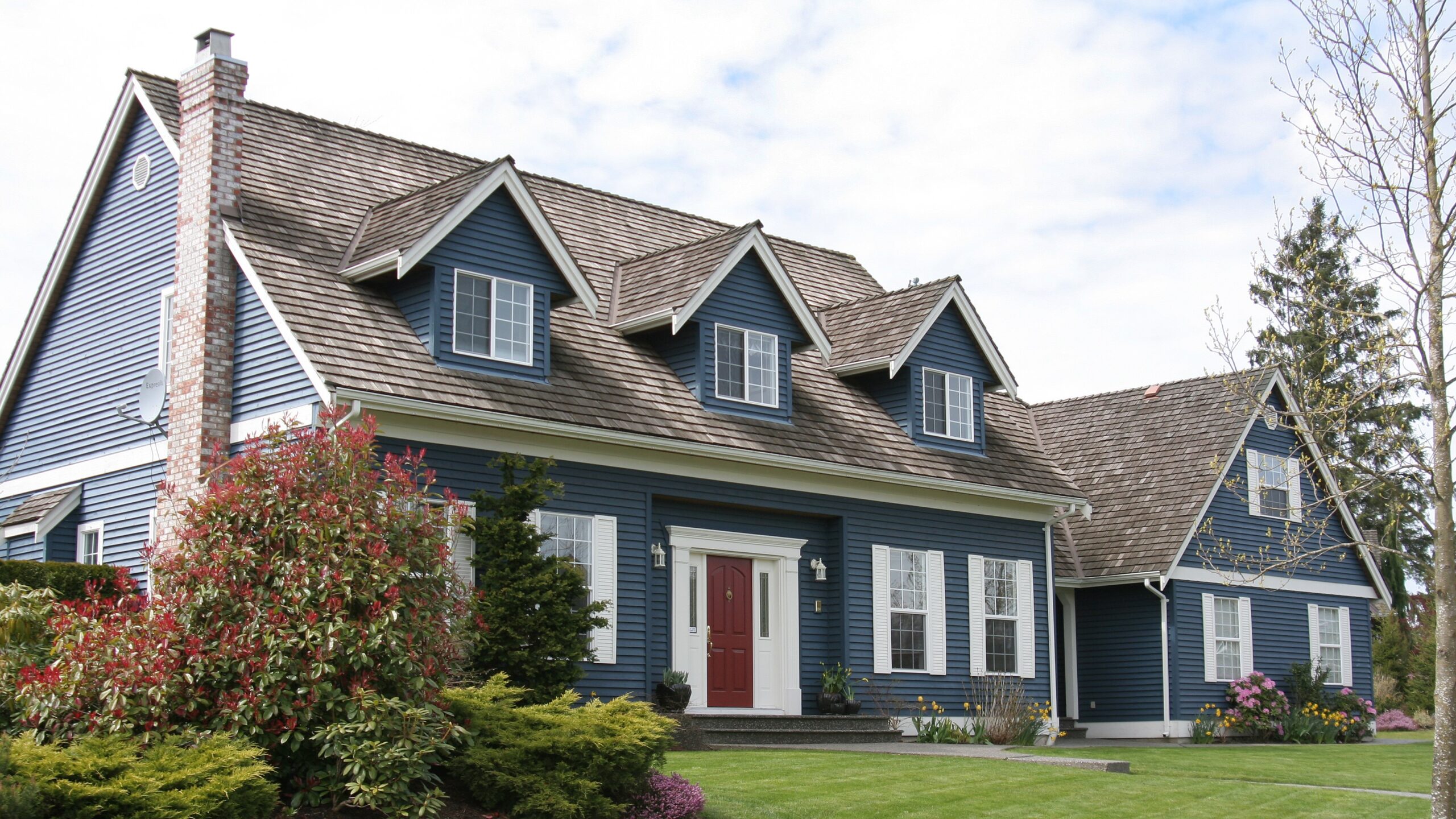 Two-story home with blue siding, red front door, and multiple windows