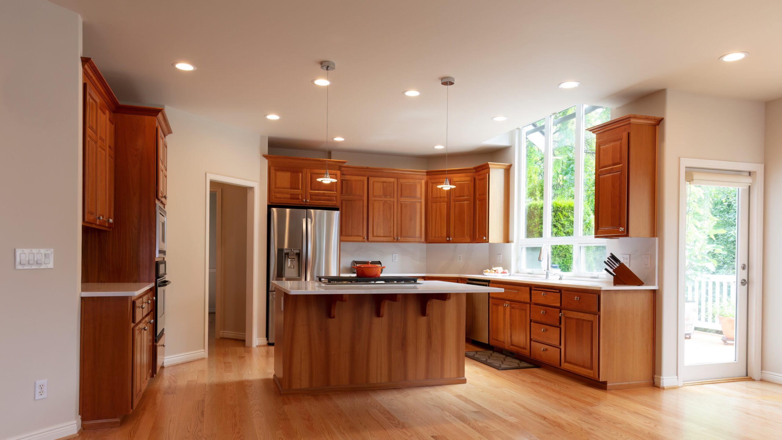 Beige kitchen with brown-stained cabinets, hardwood floors, and silver appliances
