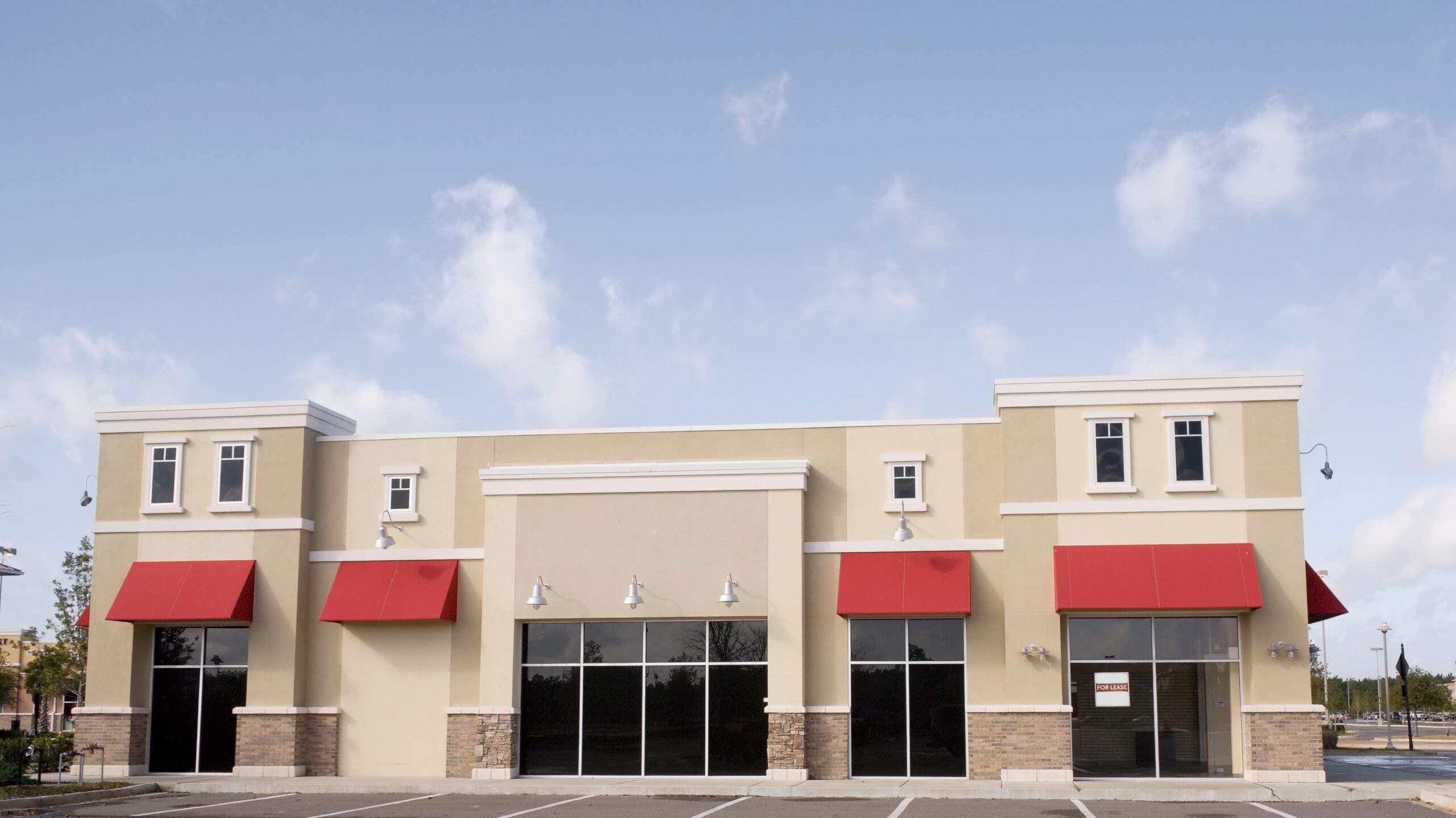 Street view of beige commercial building with red canopies