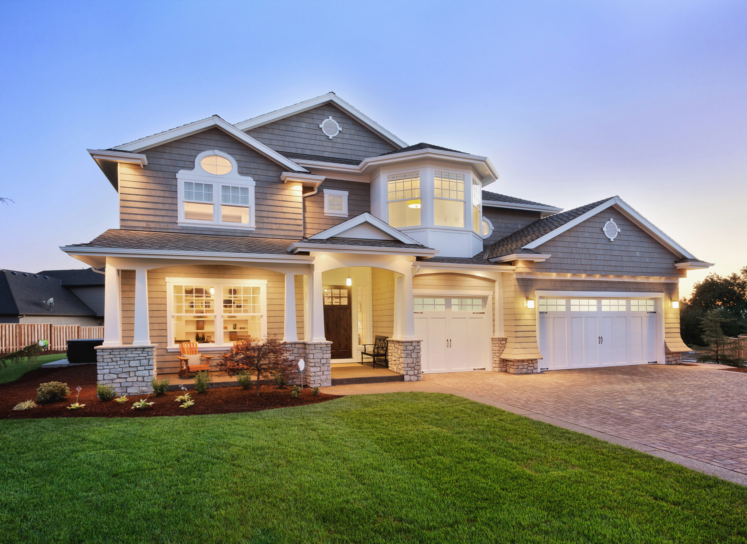 Two-story home at night with lights on