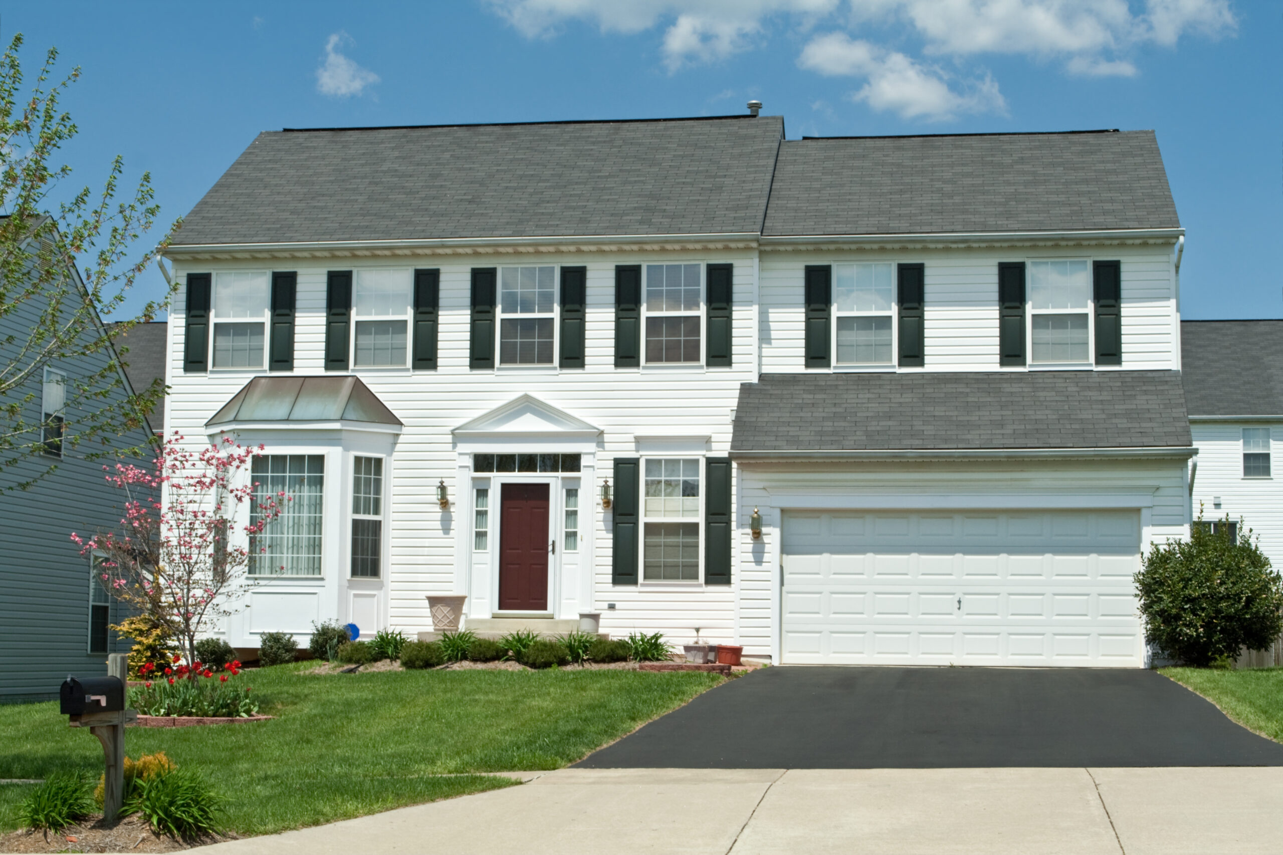 White house with asphalt shingle roof and a white garage