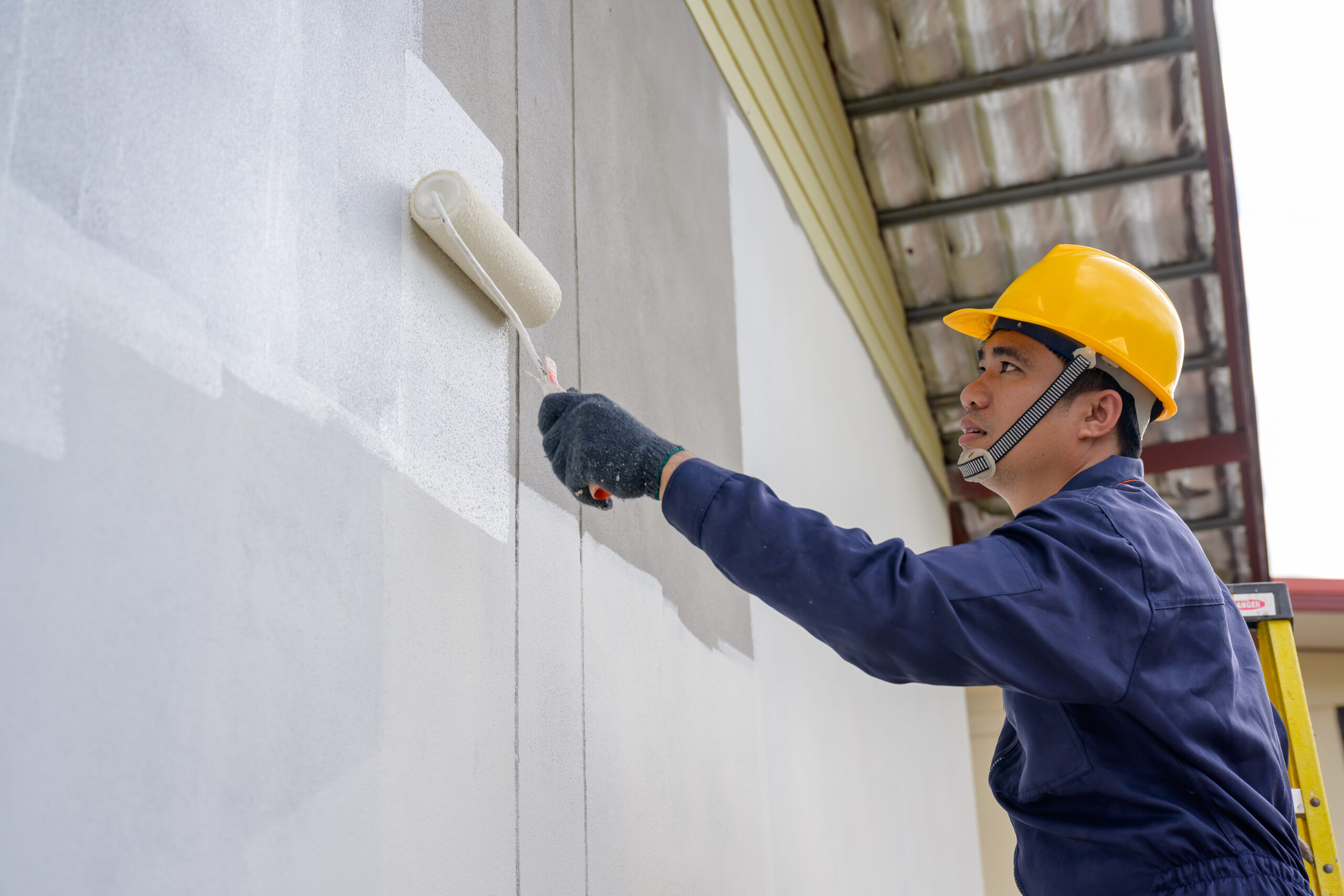 Painter painting the exterior of a house white